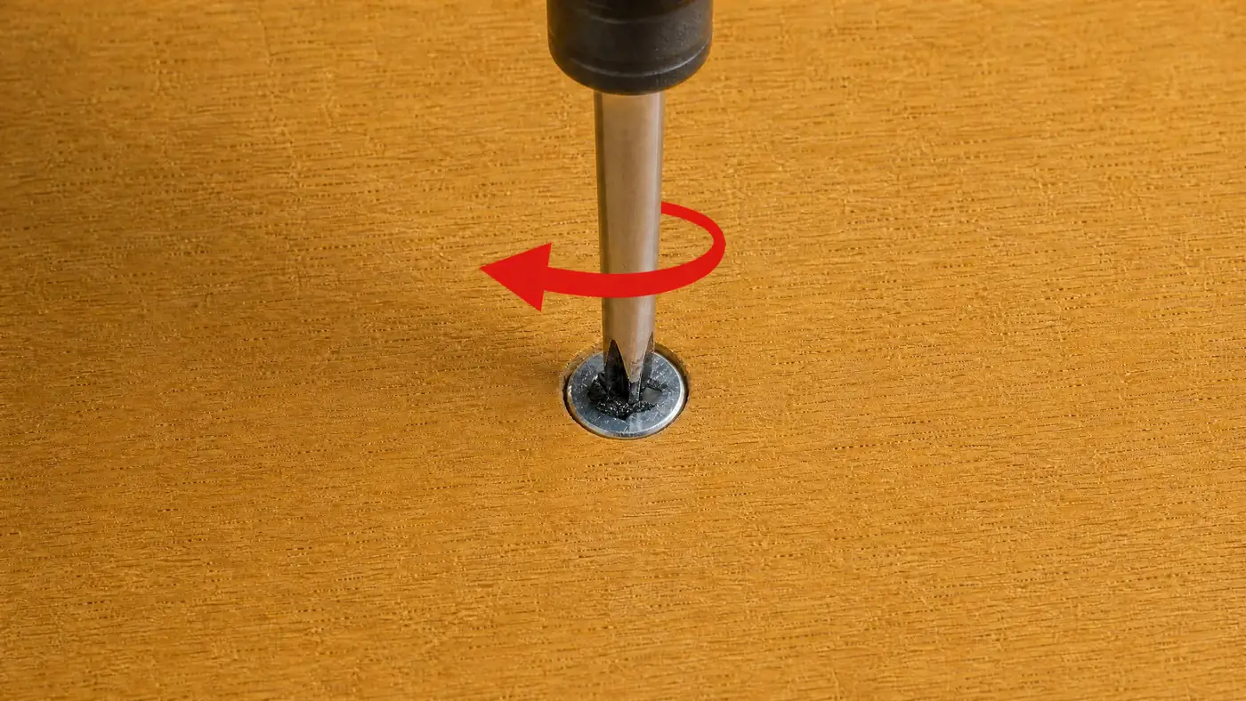Screwdriver turning counterclockwise in a stripped screw with visible grip compound