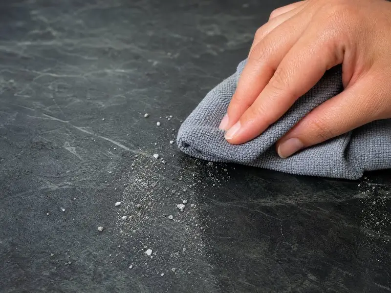 Microfiber cloth removing loose grit from a soapstone countertop